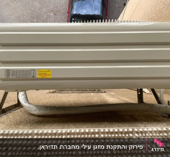 יחידת מזגן חיצונית מותקנת על קיר עם צינור מחובר